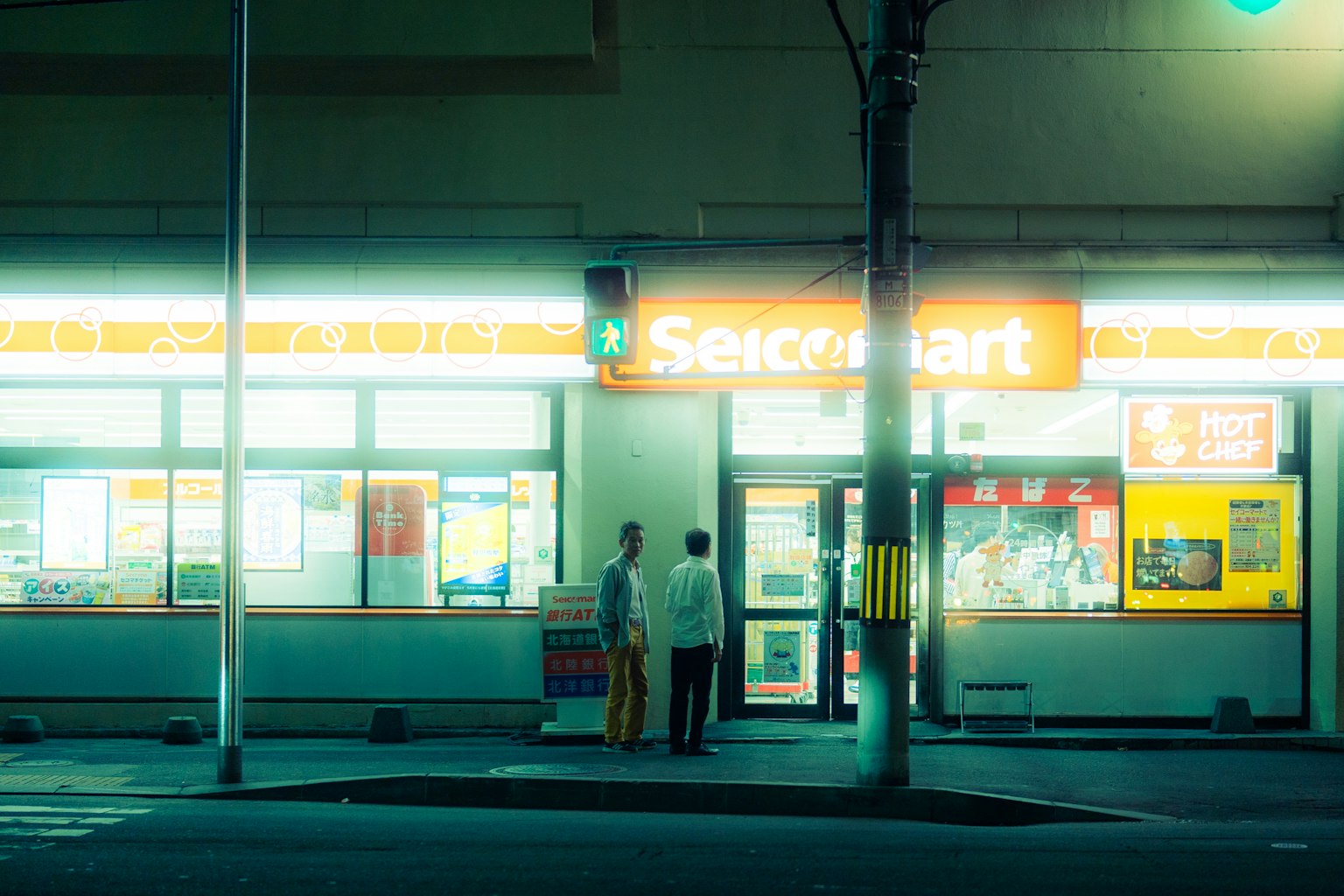 夜晚两个人站在明亮的Second Mart前面