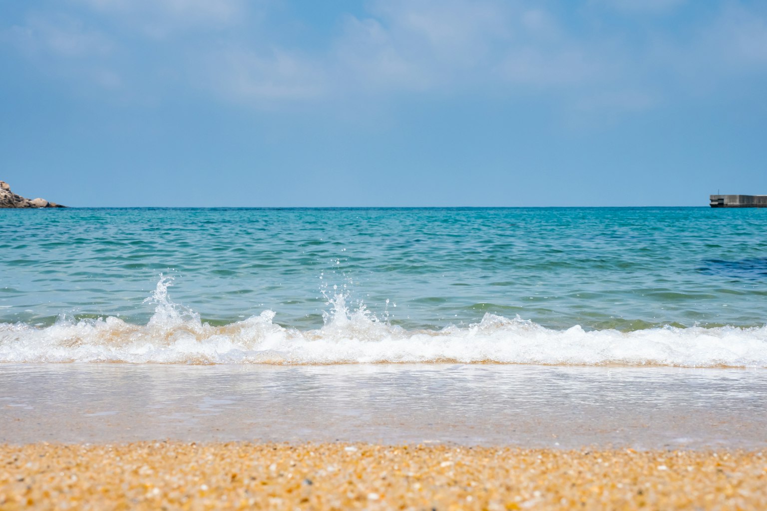 Malersicher Blick auf einen ruhigen Strand mit blauen Ozeanwellen, die sanft ans Ufer schlagen