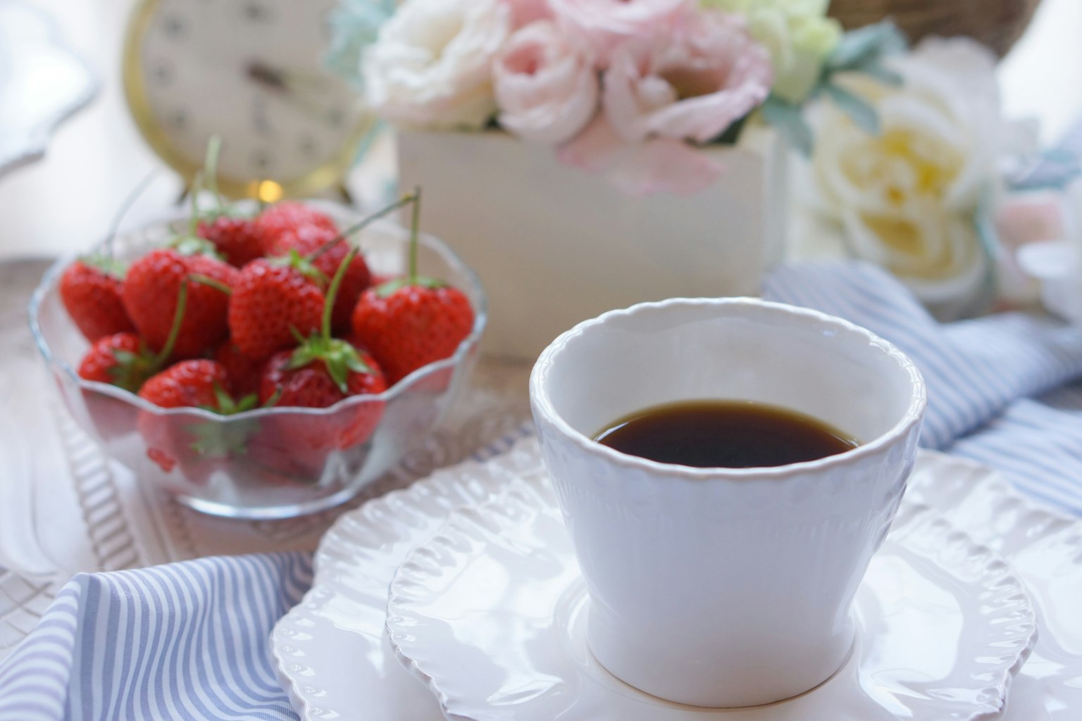Tischdekoration mit Kaffee, Erdbeeren und Blumenarrangement