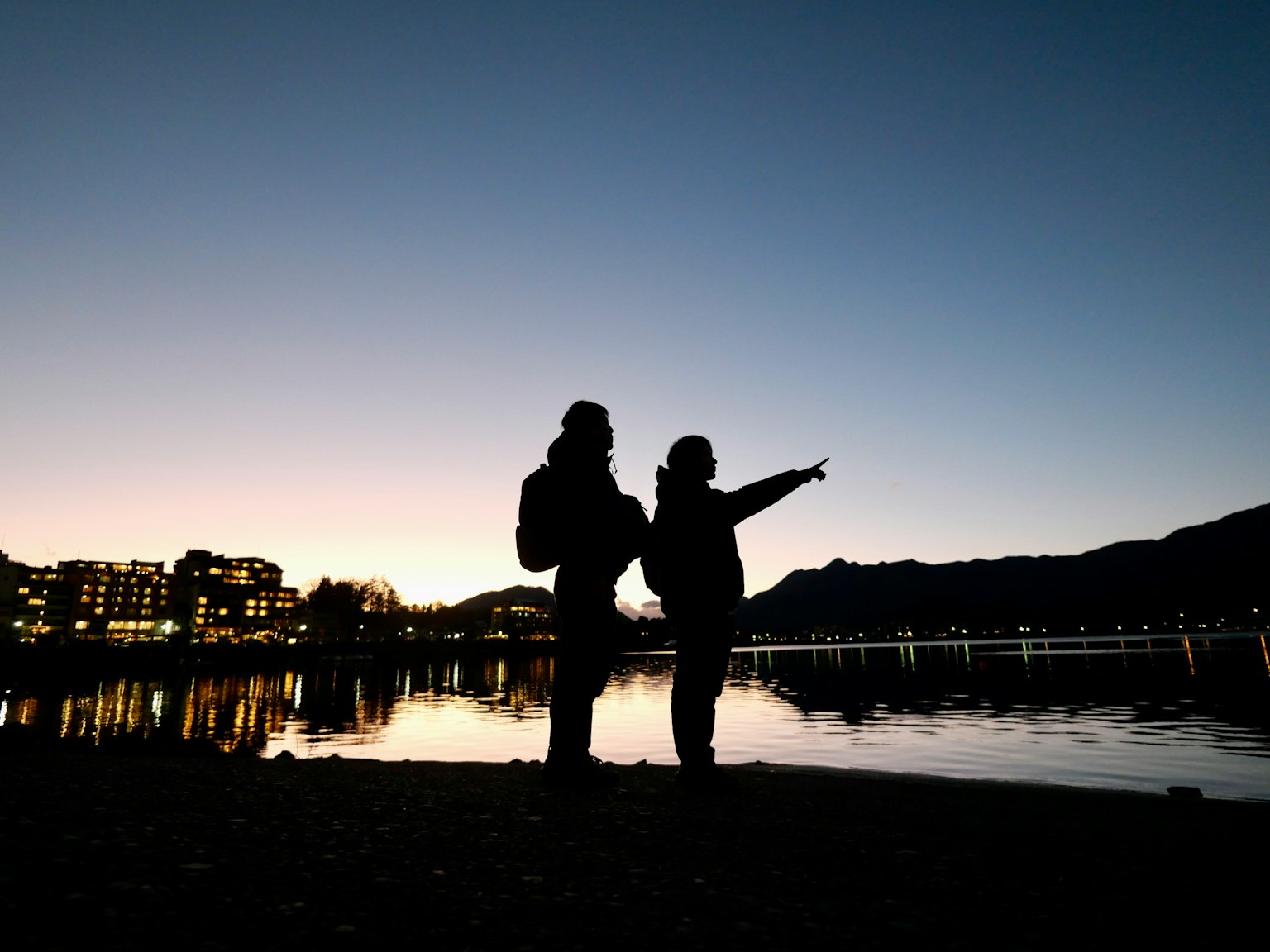 Silhouettes de deux personnes debout au bord du lac au crépuscule