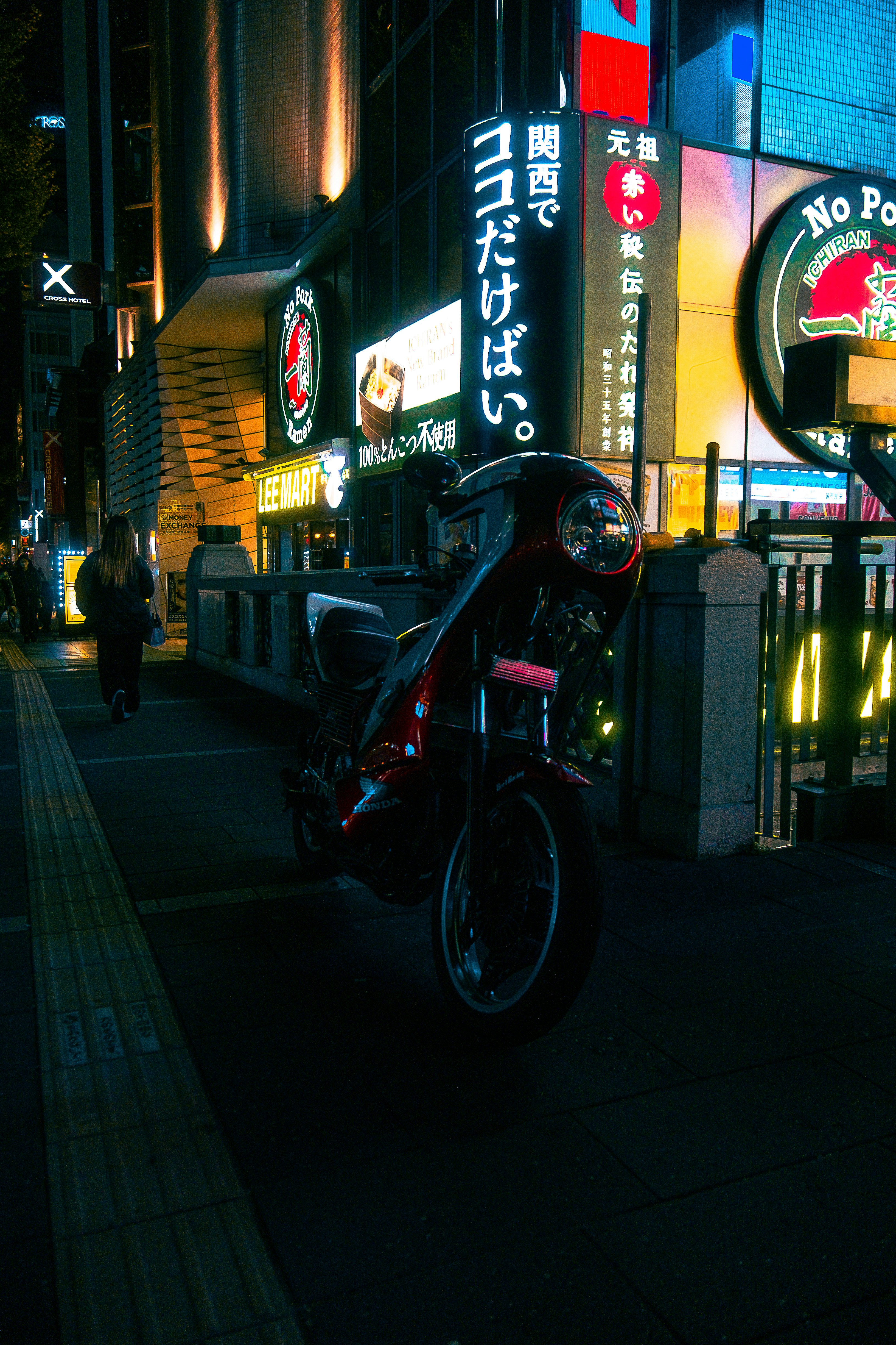 Neonbeleuchtete Gasse bei Nacht mit geparktem Motorrad und Ladenschildern