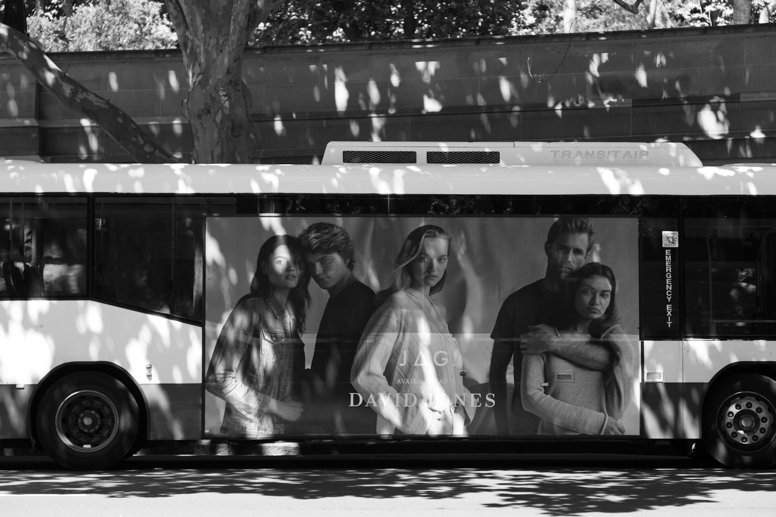Pubblicità in bianco e nero sul lato di un autobus con un gruppo di persone in un momento emotivo