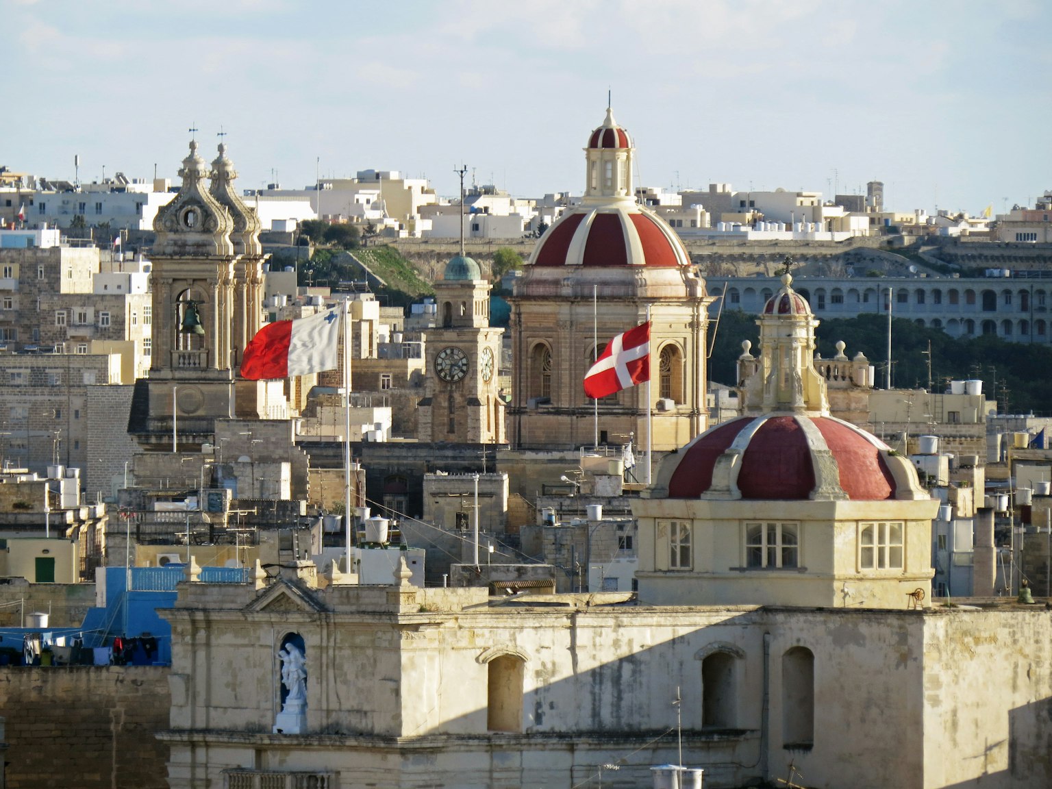 Blick auf historische Gebäude in Malta mit Kuppeldächern und Flaggen