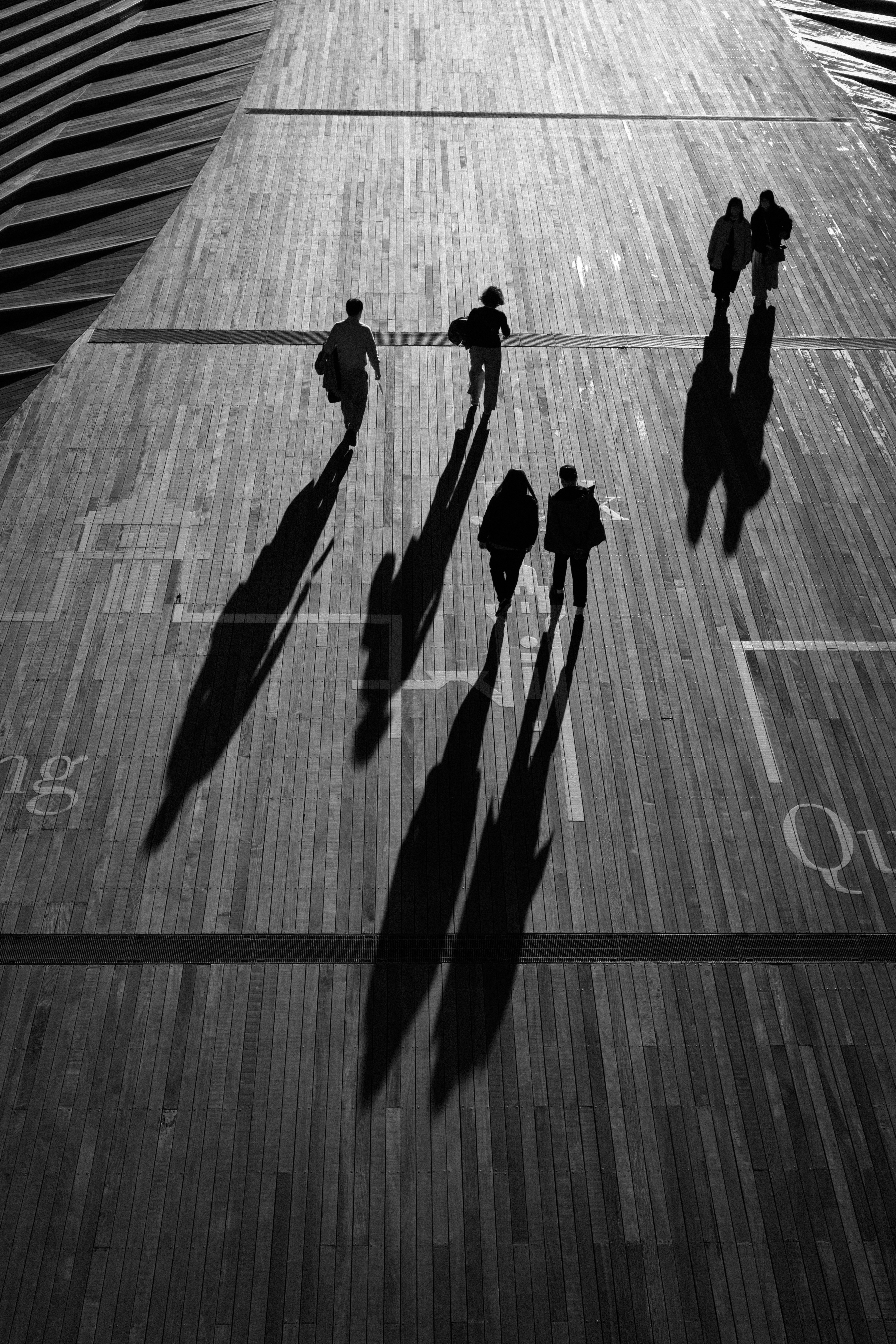 silhouetted people walking on a wooden floor