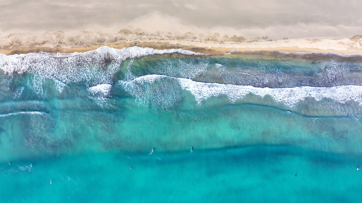 Vista aérea de las olas turquesas del océano y la playa de arena