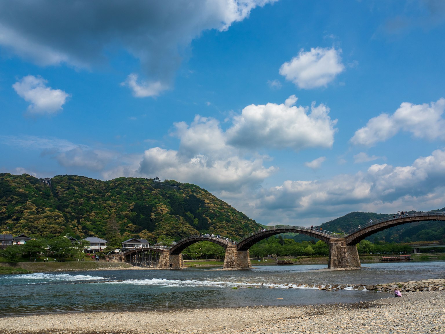 Vista panoramica di un ponte ad arco su un fiume con montagne sullo sfondo