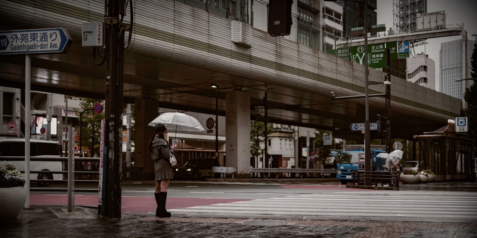 一位手持雨傘的女性站在城市雨天的斑馬線上