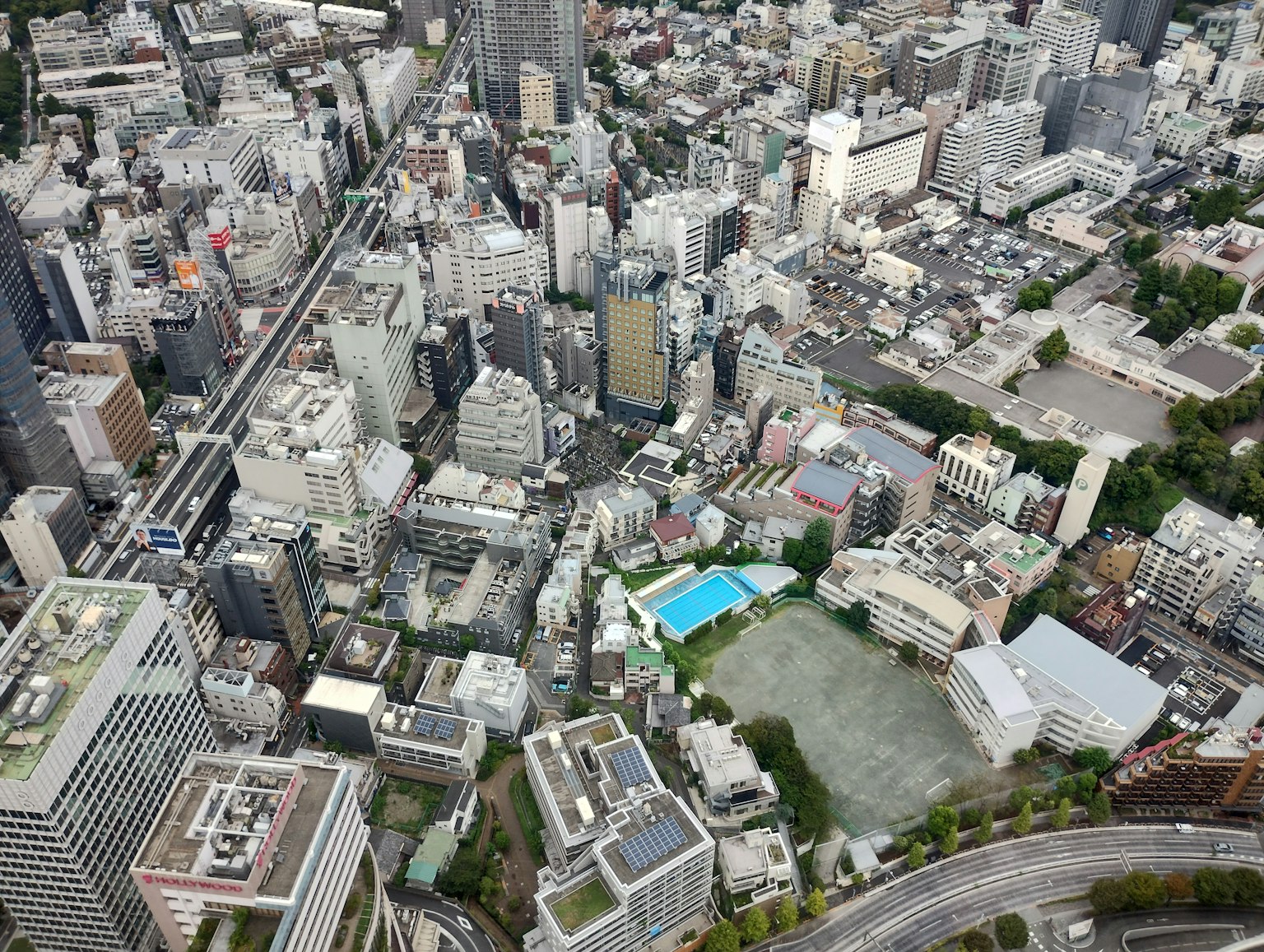 Vista aérea de un paisaje urbano con edificios altos que incluyen un parque y una piscina