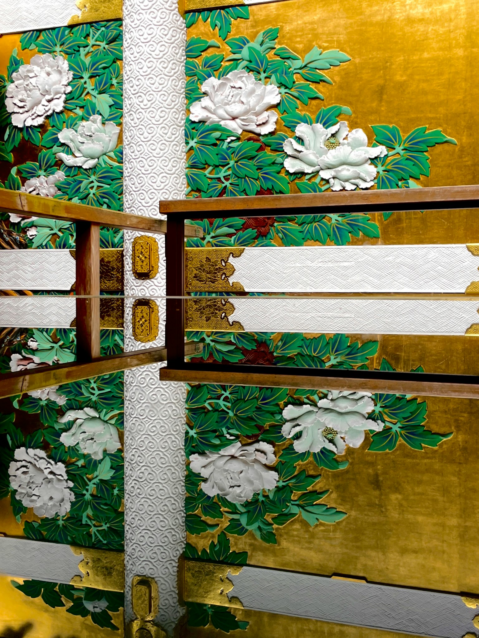 金色の背景に白い花と緑の葉の装飾が施された壁の前にある木製のテーブル