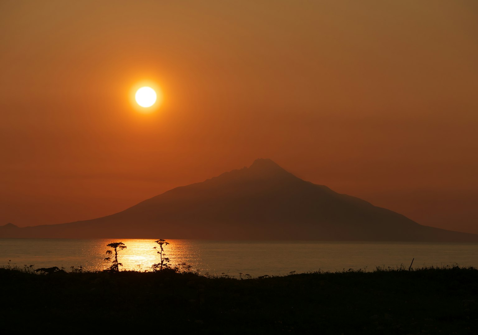 Vue panoramique d'un coucher de soleil sur une montagne se reflétant dans l'eau calme