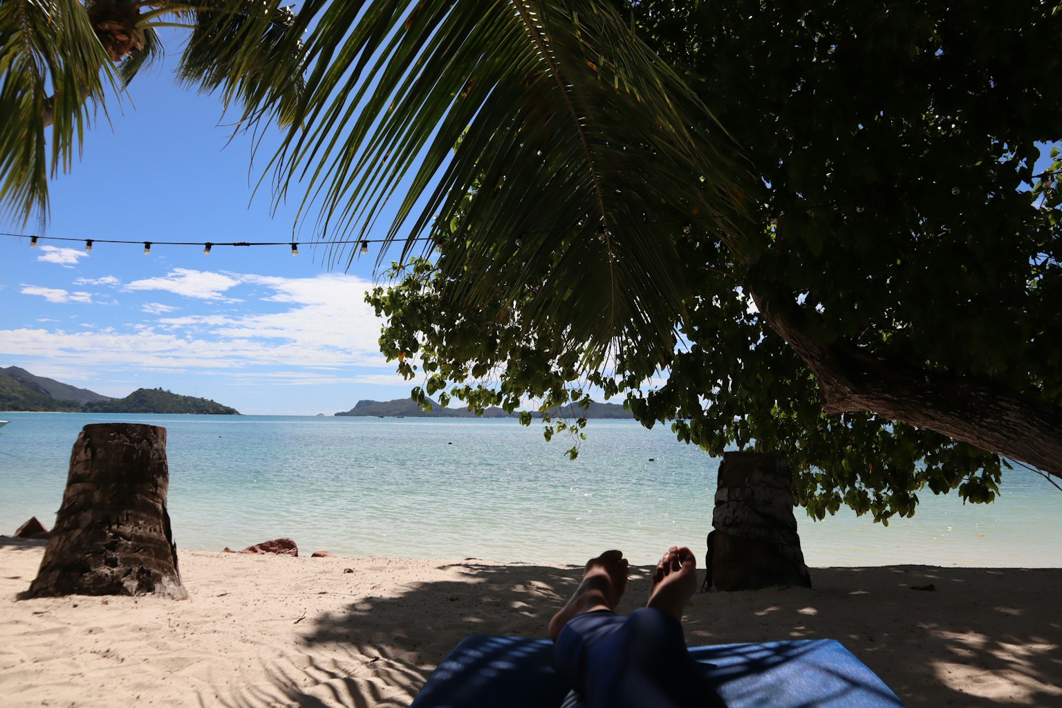 Person's feet relaxing on a beach with a blue ocean view