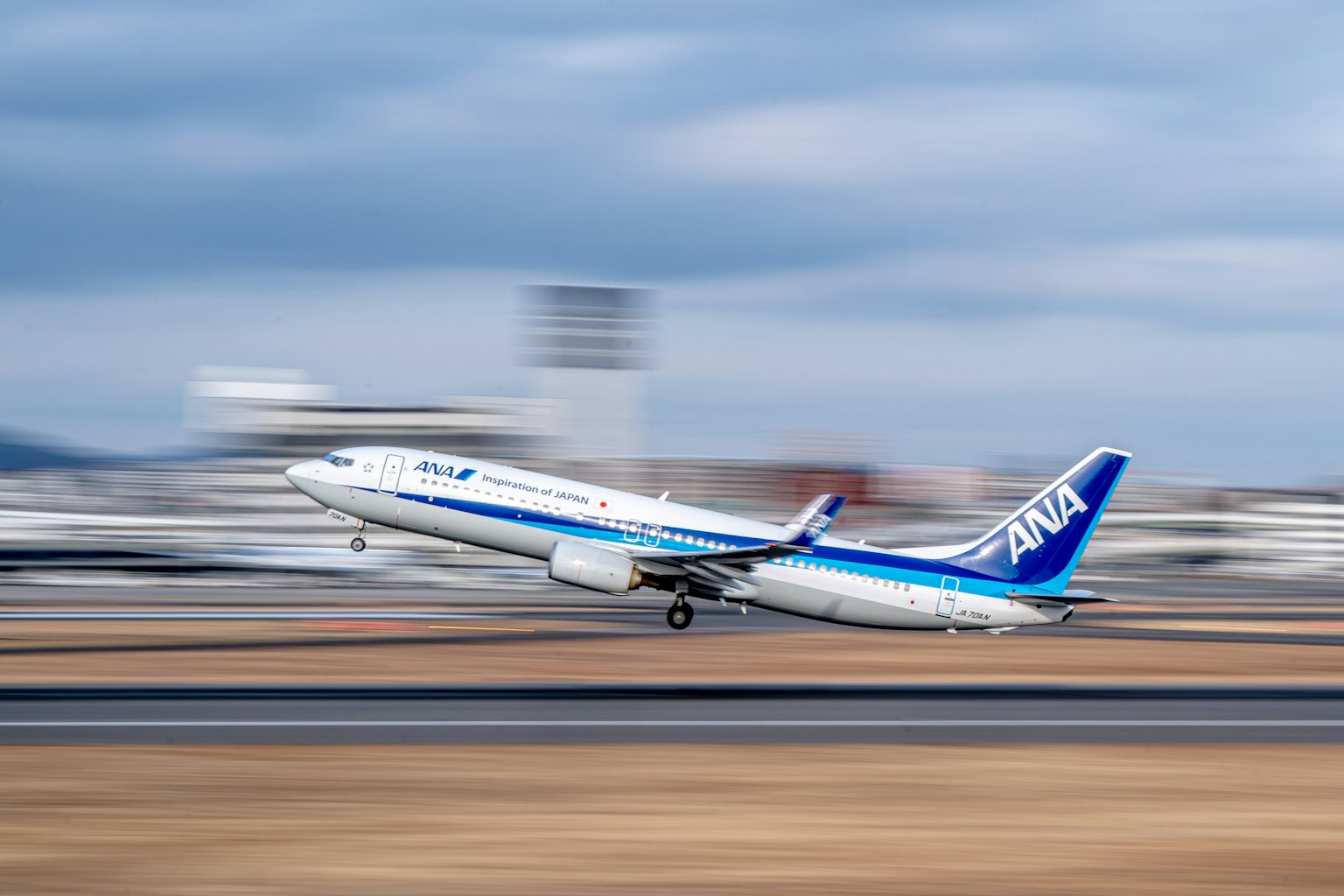 Aereo passeggeri ANA in fase di decollo dalla pista con cielo nuvoloso