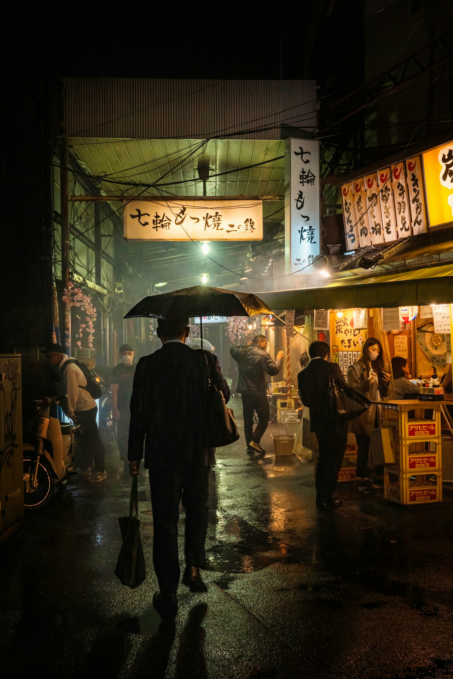 一个拿着雨伞的男人在雨中走过夜市