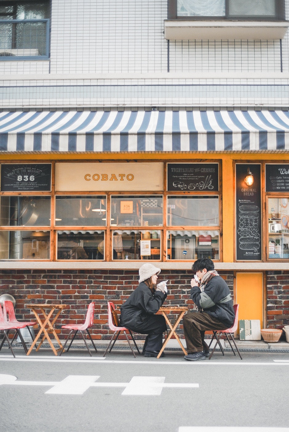 路地のカフェ前でベンチに座る人たち