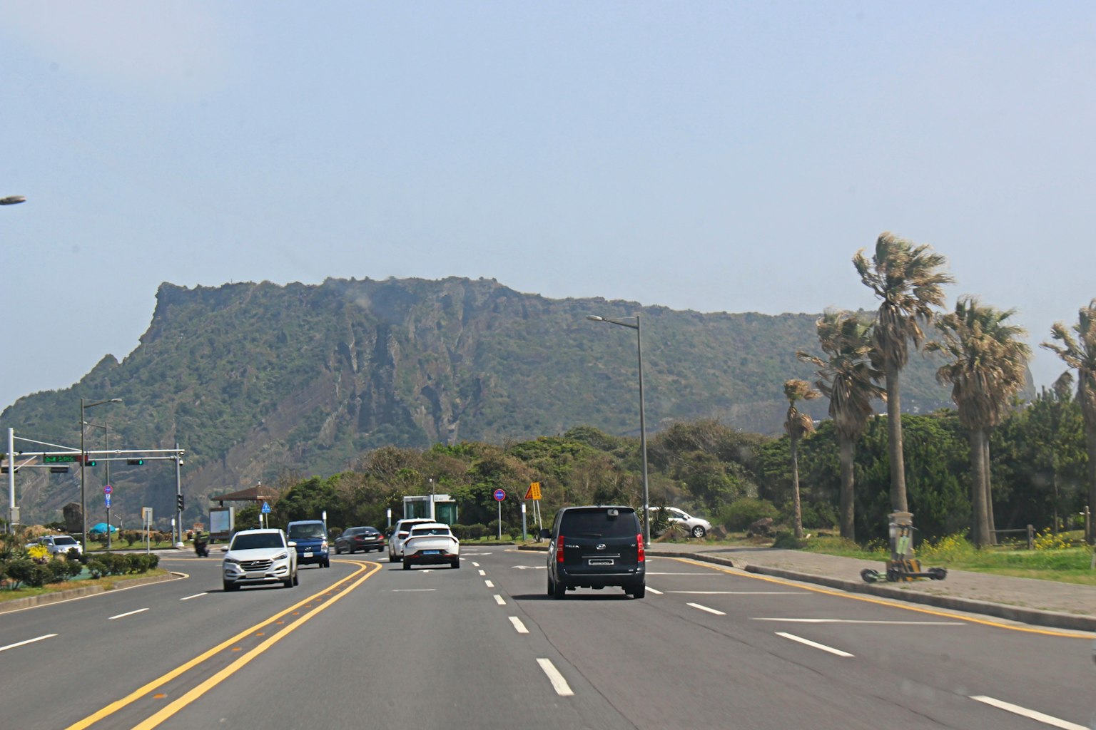 Scenic view of a road with cars and a mountain in the background