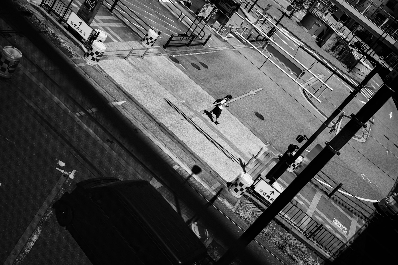 Escena de calle en blanco y negro con una persona cruzando la carretera