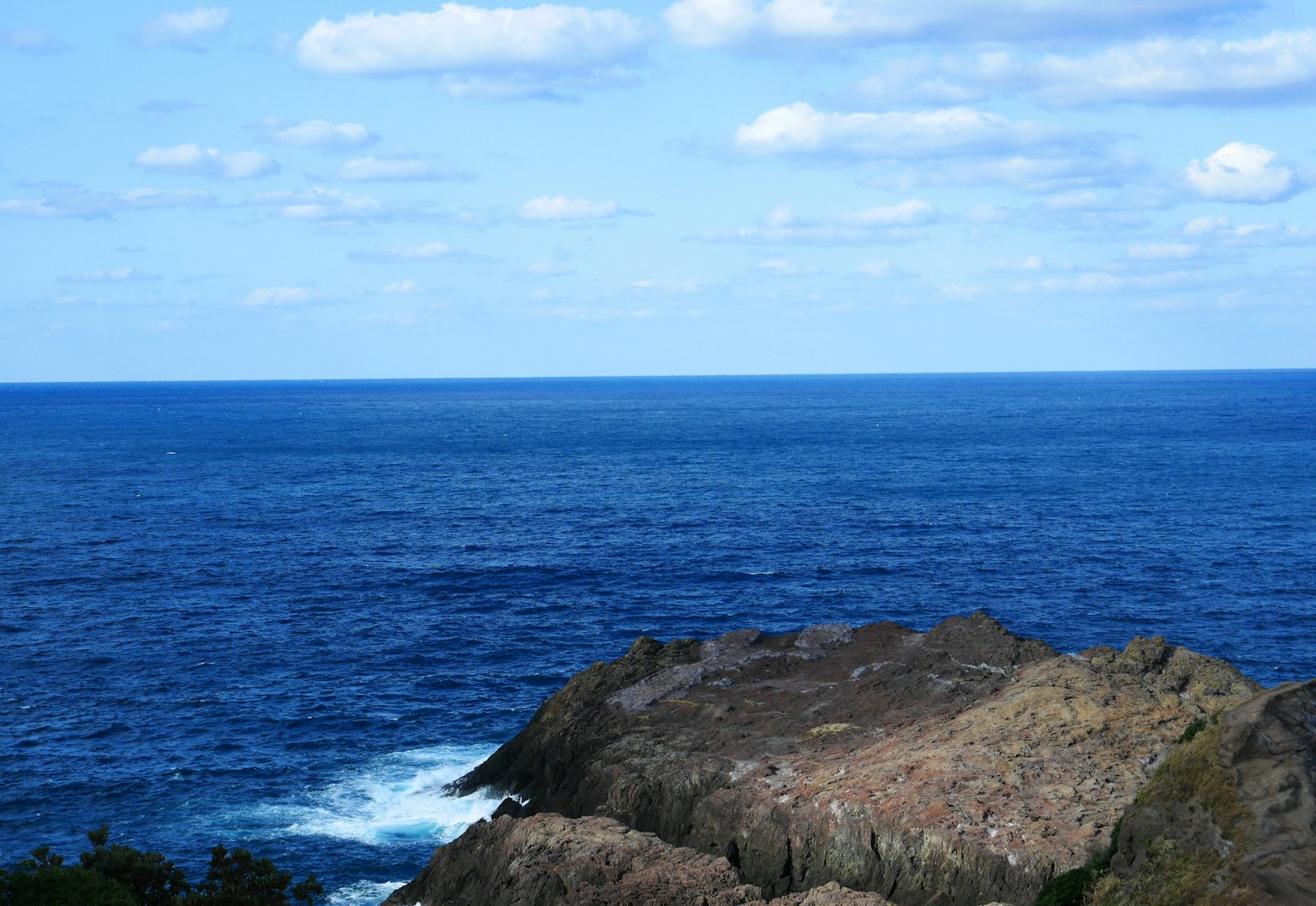 Vue panoramique de l'océan bleu et du ciel nuageux avec un premier plan rocheux