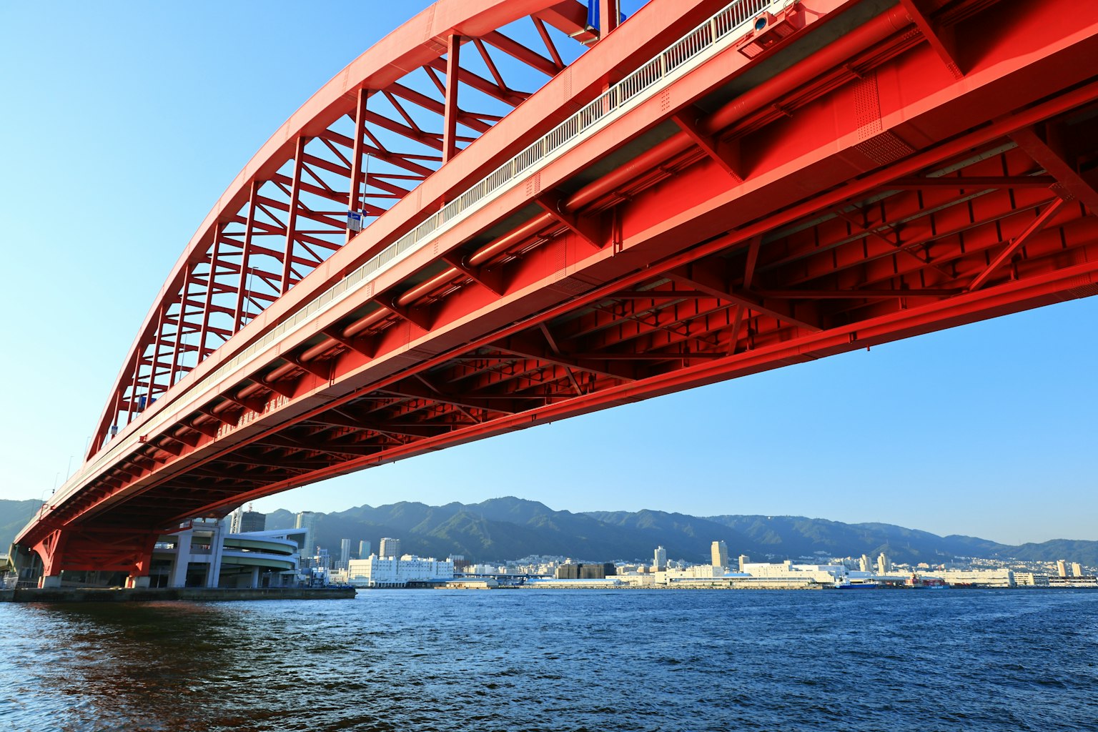 Un ponte ad arco rosso che attraversa l'acqua sotto un cielo blu