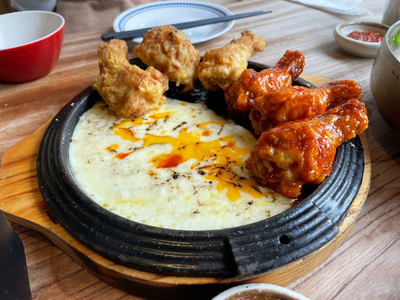 Un piatto sfrigolante con ali e cosce di pollo fritto su una base cremosa