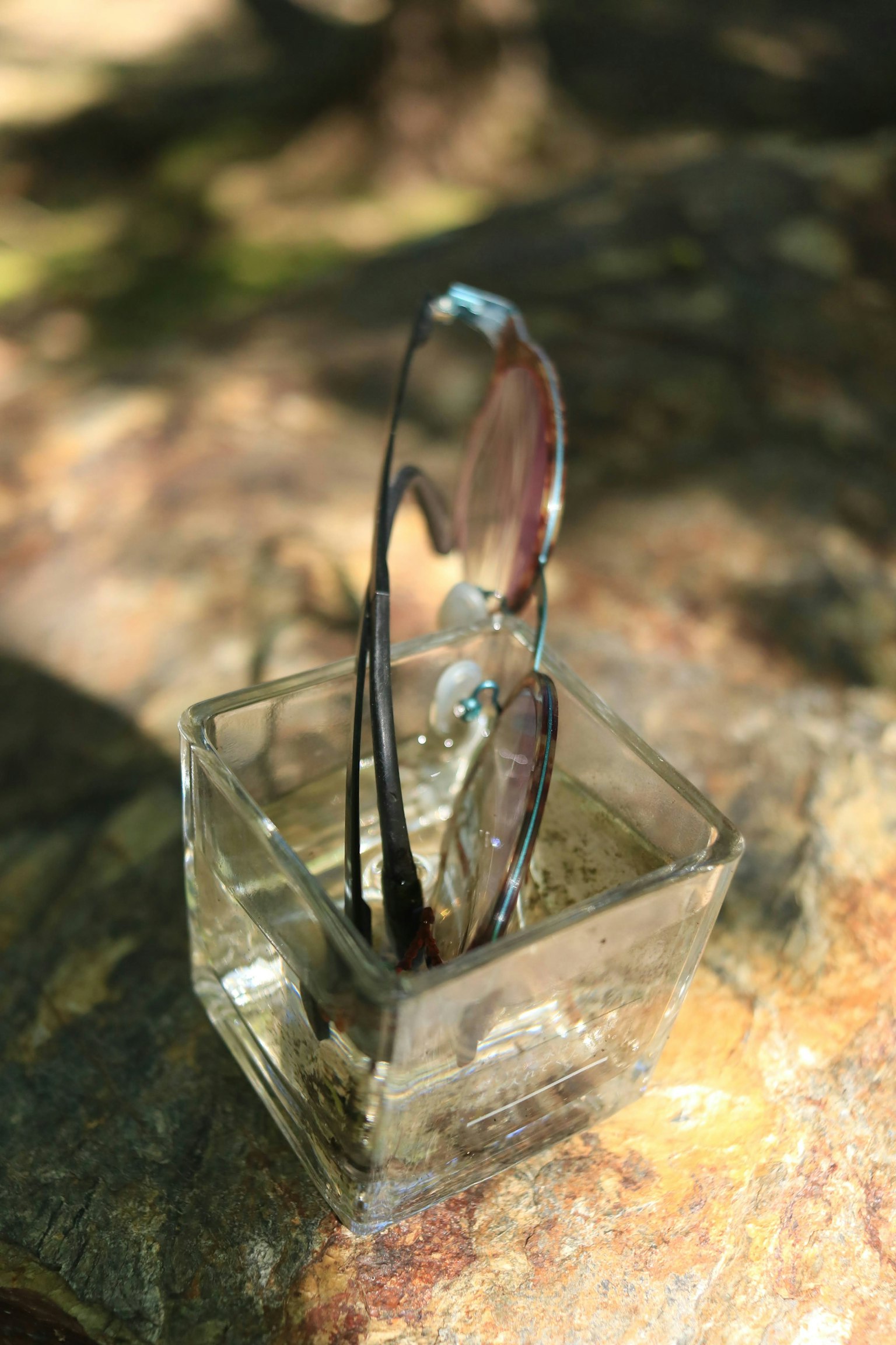Lunettes de soleil reposant dans un verre transparent réfléchissant la lumière