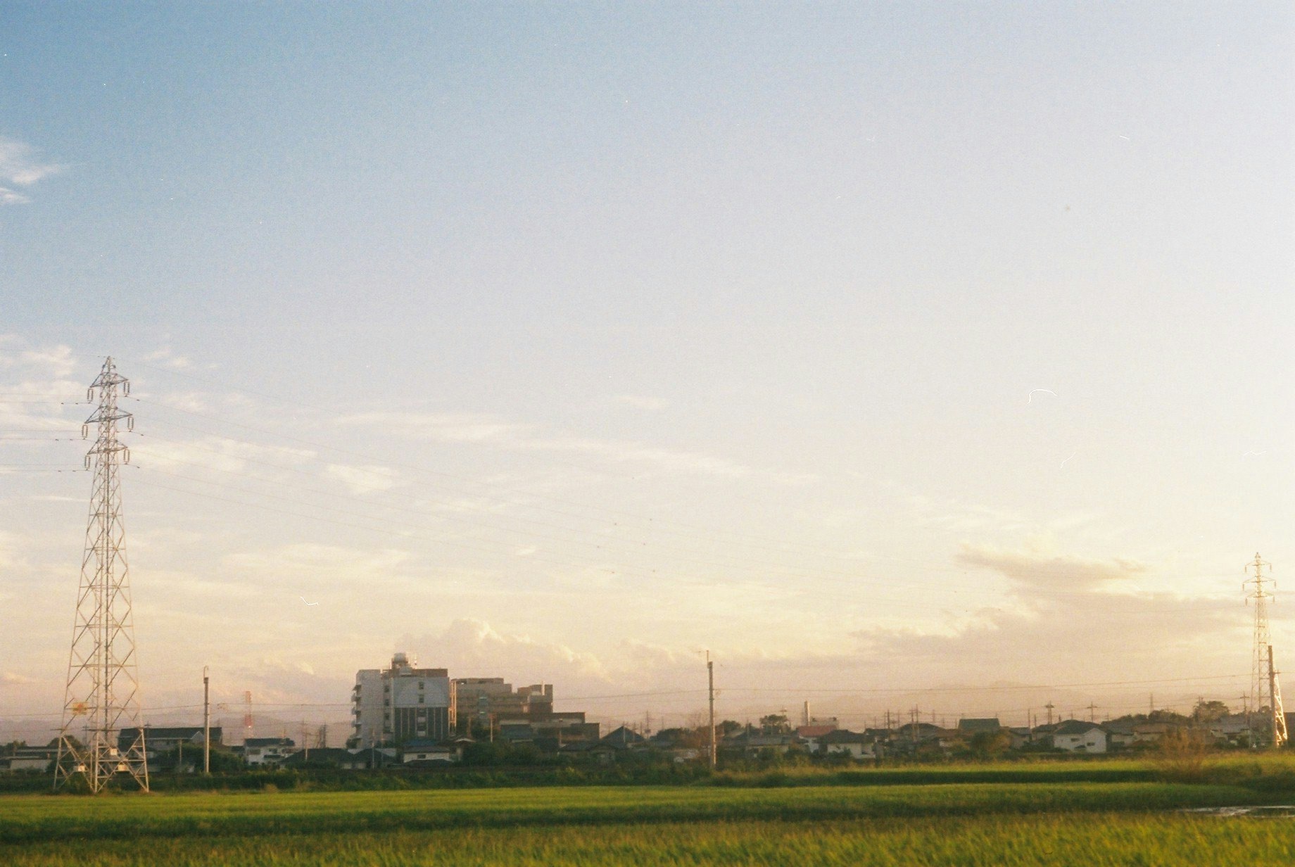 夕暮れの田園地帯と送電鉄塔が並ぶ風景