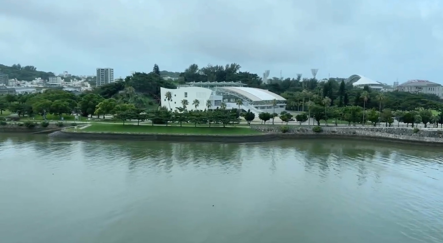 A scenic view featuring a white building along a riverside green space