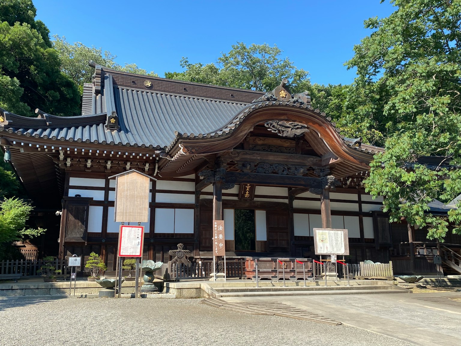 传统日本建筑外观，周围环绕着郁郁葱葱的绿色树木