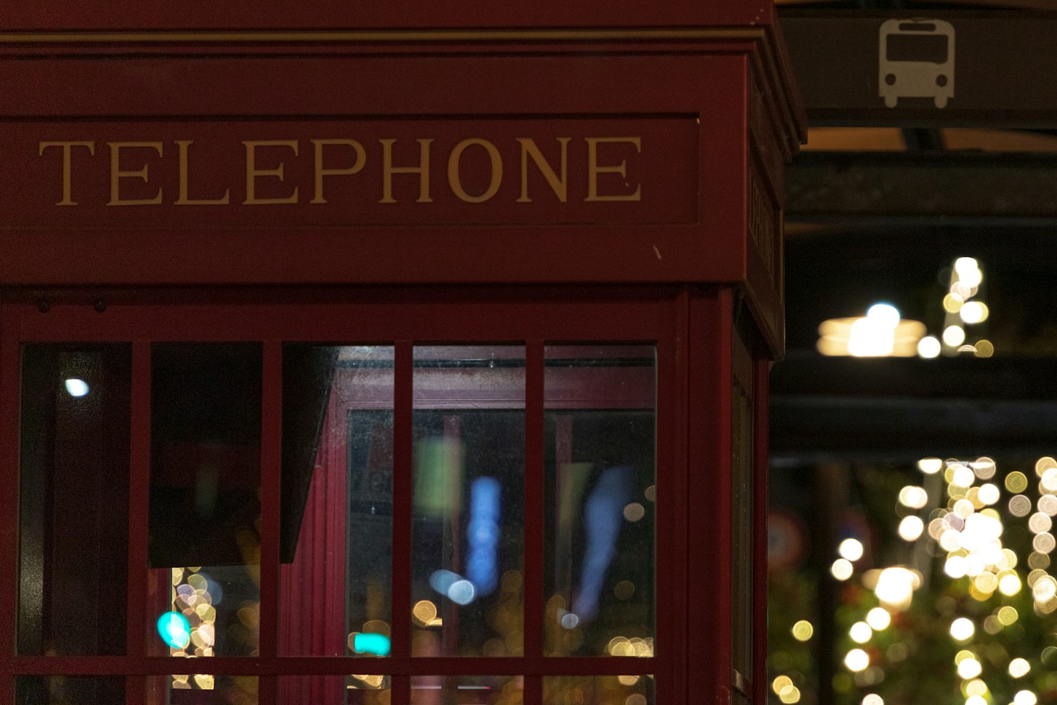 Cabina telefonica rossa con luci notturne sullo sfondo