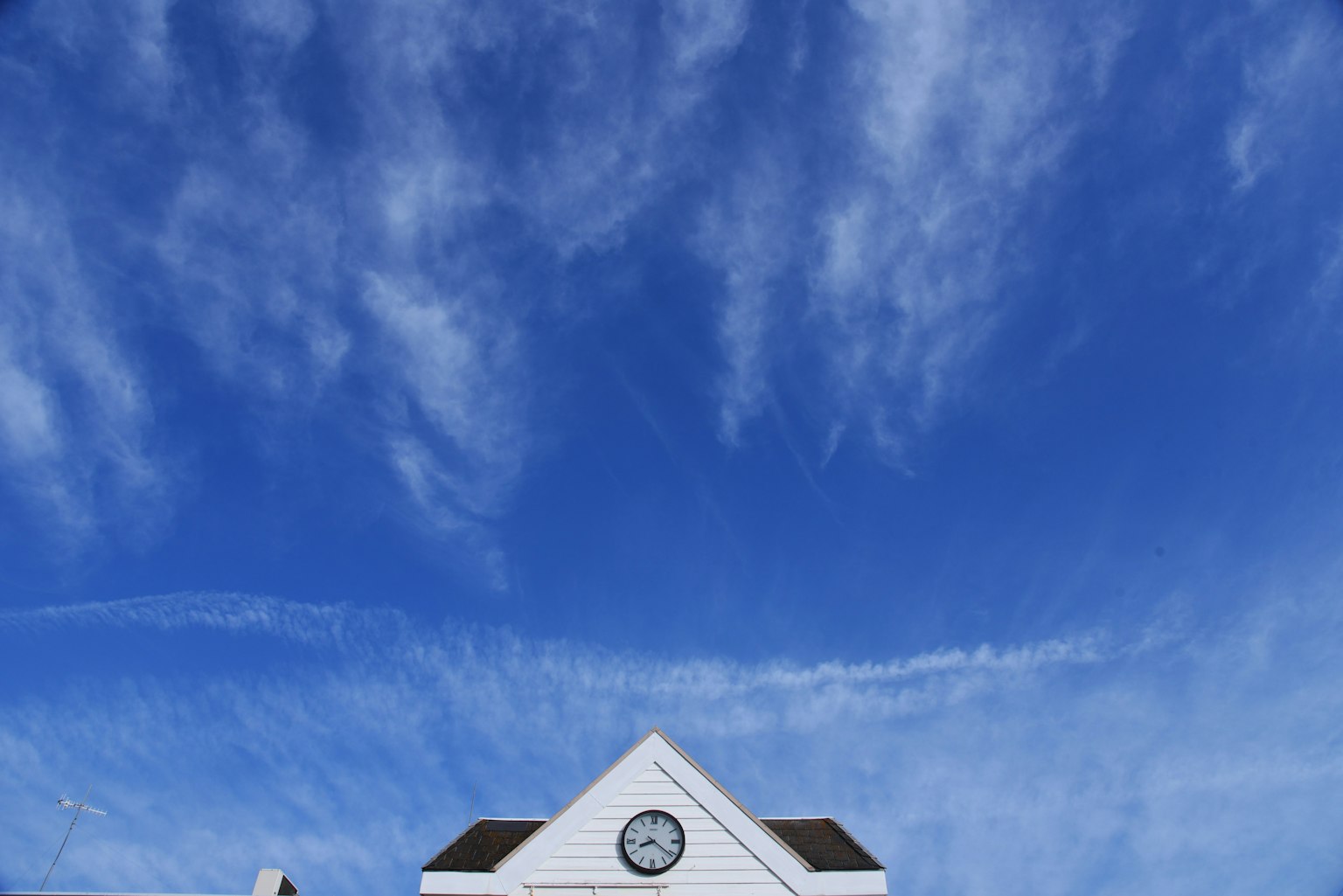 Weißes Haus mit einer Uhr unter einem blauen Himmel