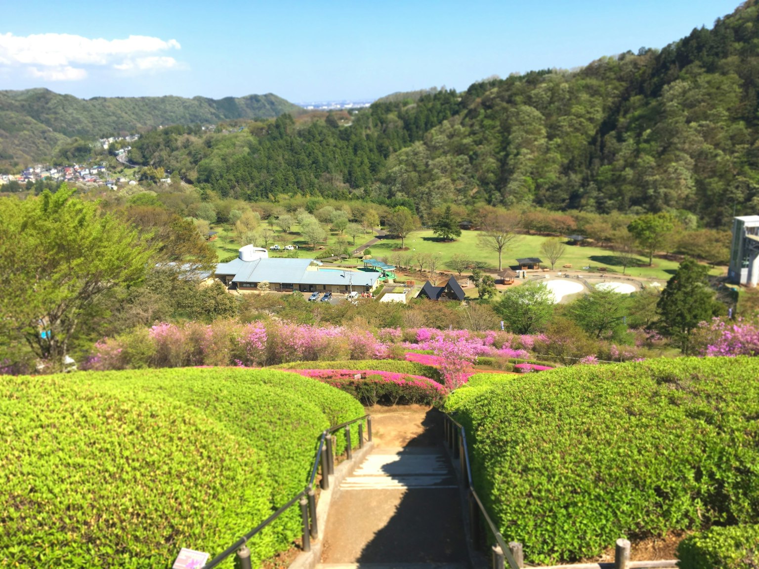 被群山環繞的風景如畫的花園景觀，綠意盎然，花卉色彩斑斕