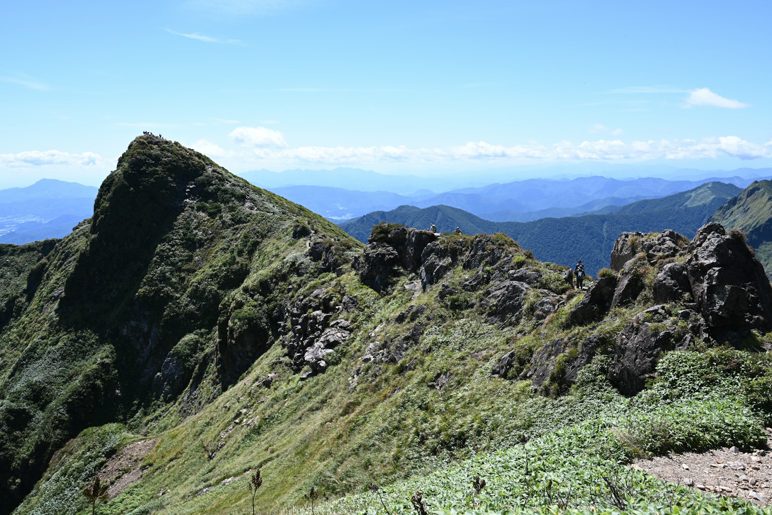 Vista de montañas verdes y pendientes rocosas bajo un cielo azul