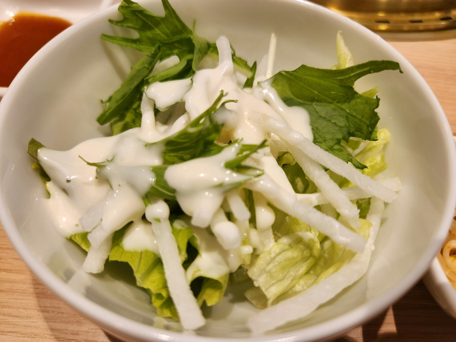 A bowl of fresh salad with lettuce and dressing on top
