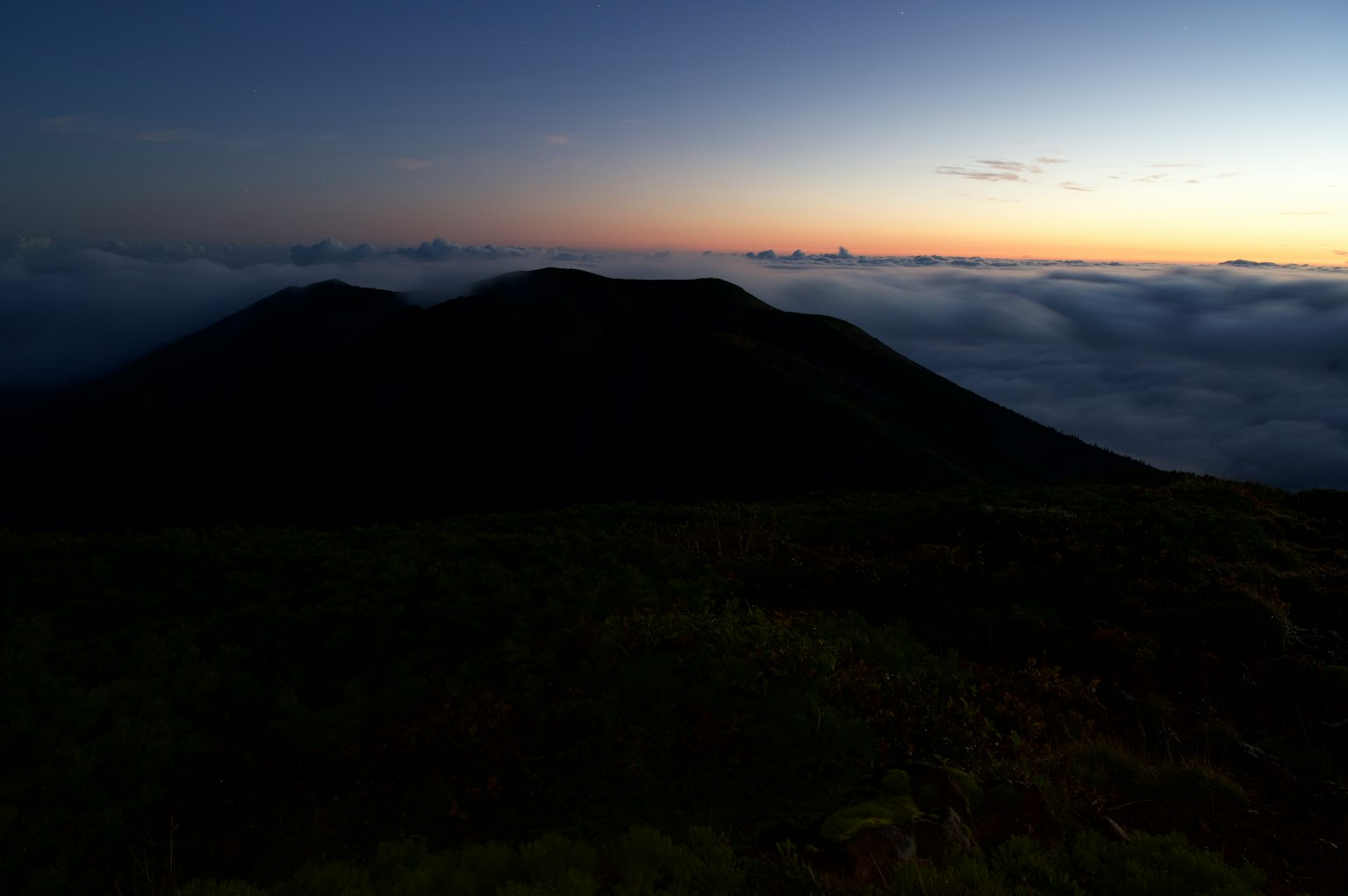 Silueta de montañas sobre un mar de nubes al atardecer