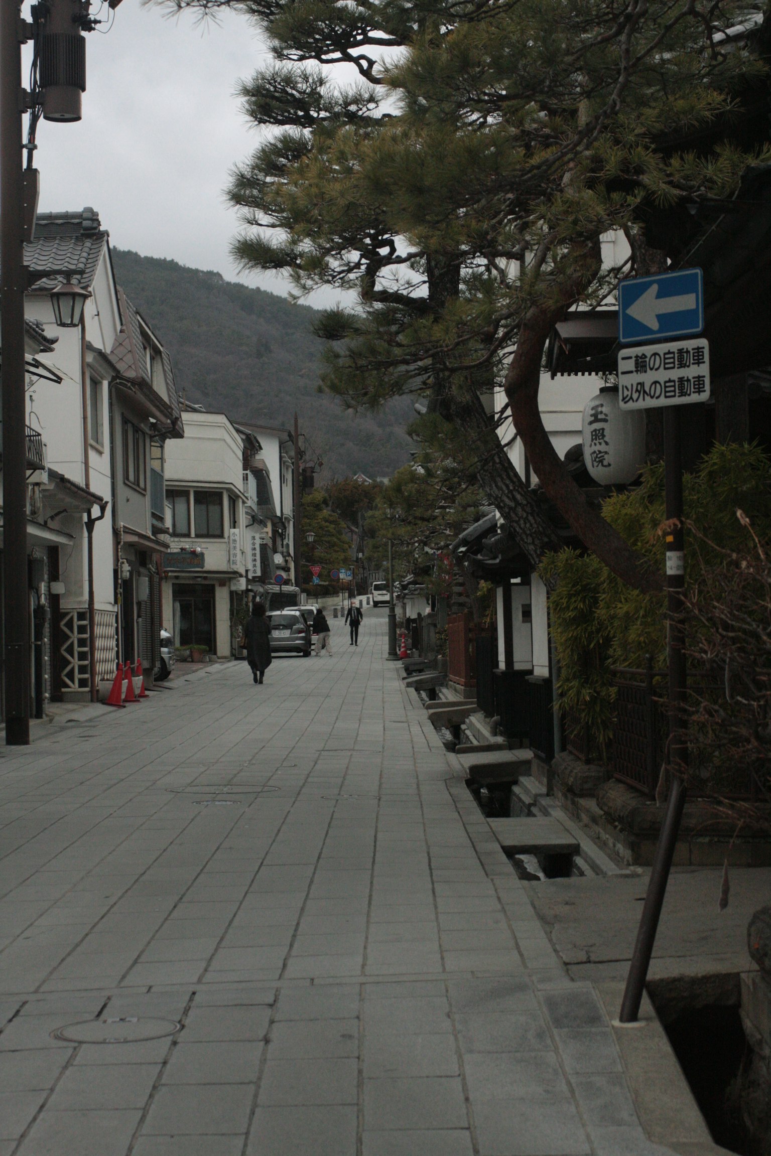 ภาพถนนที่เงียบสงบ มีอาคารสีขาวและถนนปูพื้น มีภูเขาอยู่ด้านหลัง