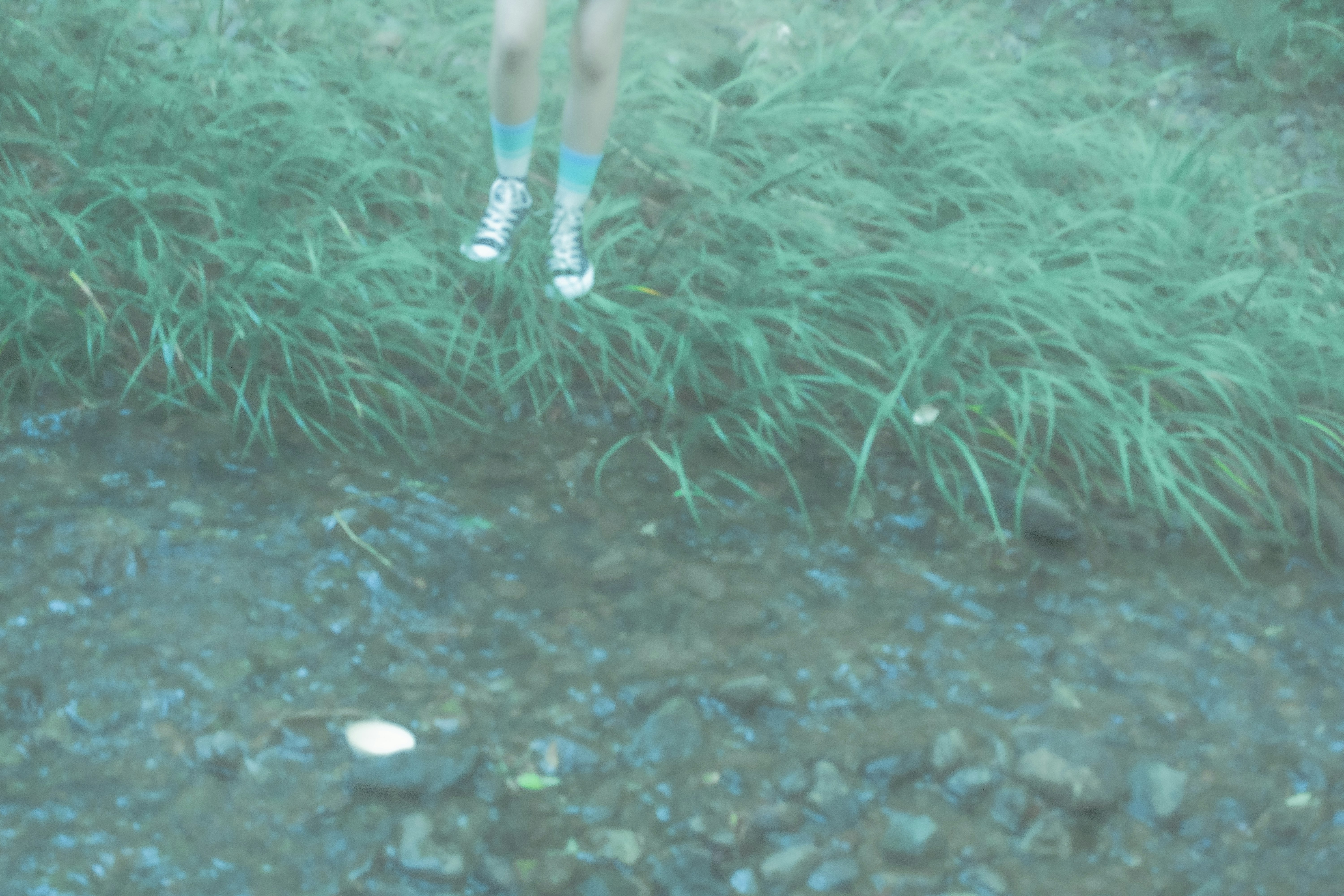 水中の草むらと足元の人の脚