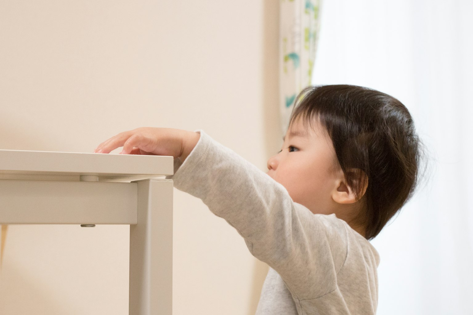 Un niño pequeño alcanzando una mesa en interiores