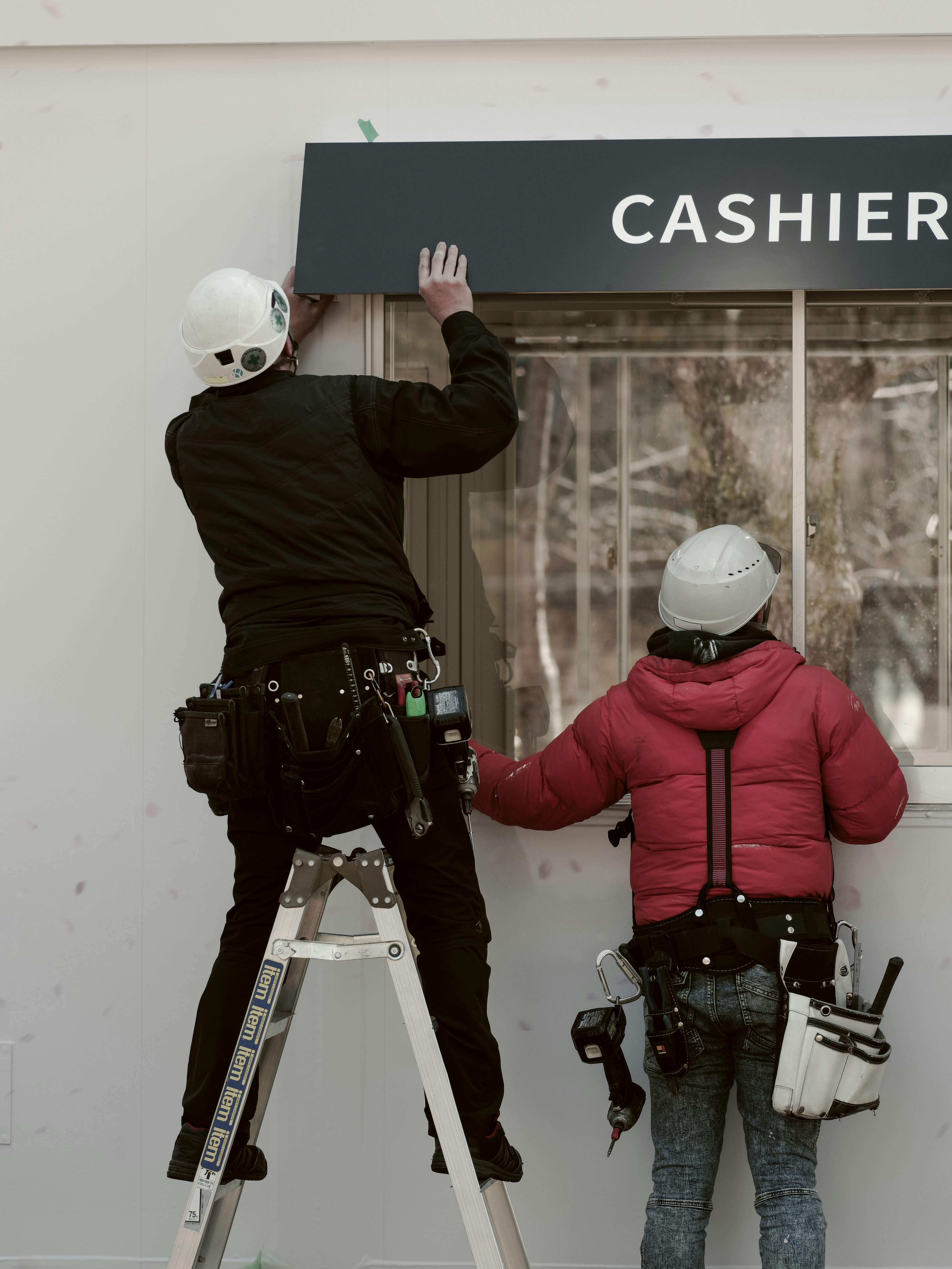 Robots waving at a storefront counter with a “CASHIER” sign