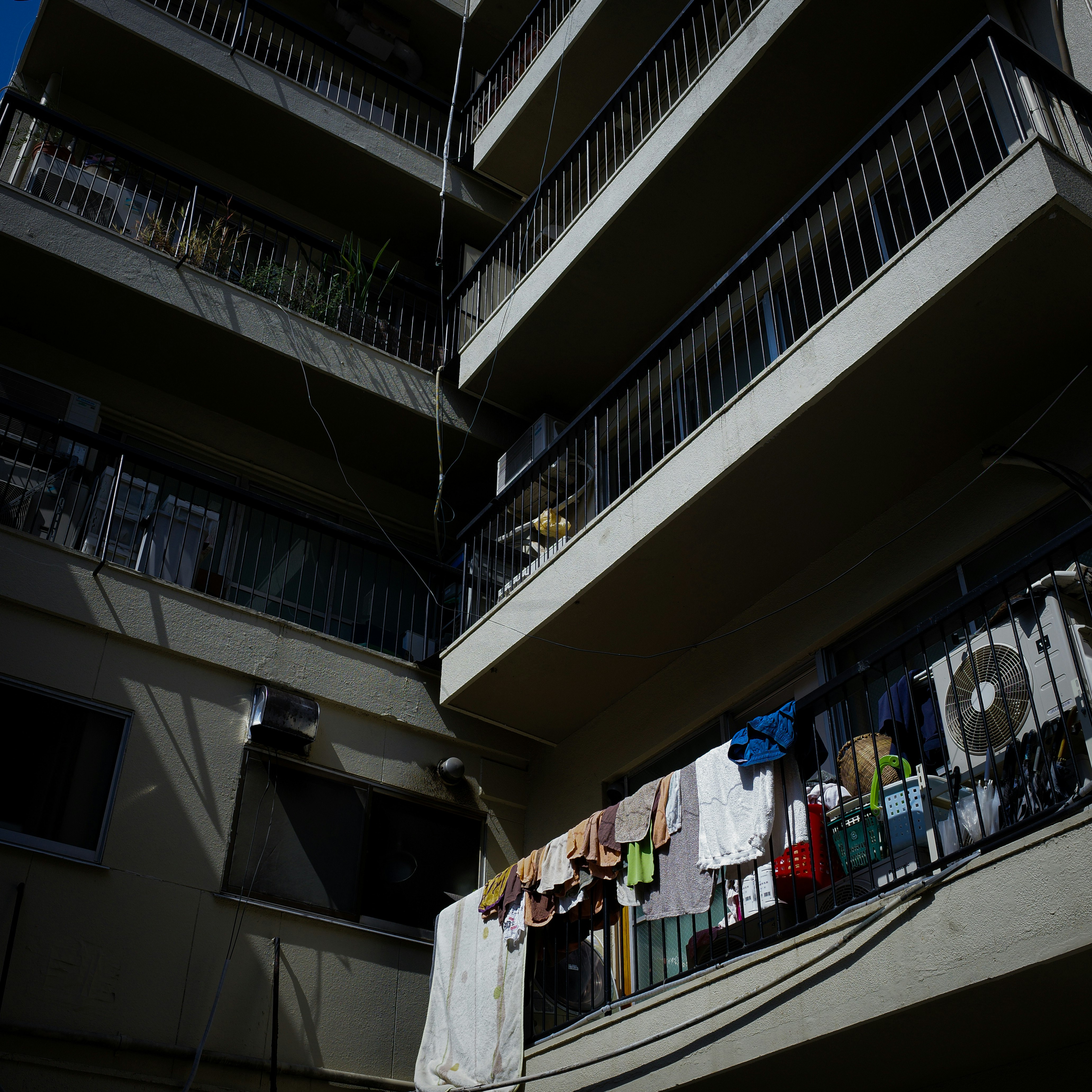 洗濯物が干された集合住宅のベランダと路地のような中庭