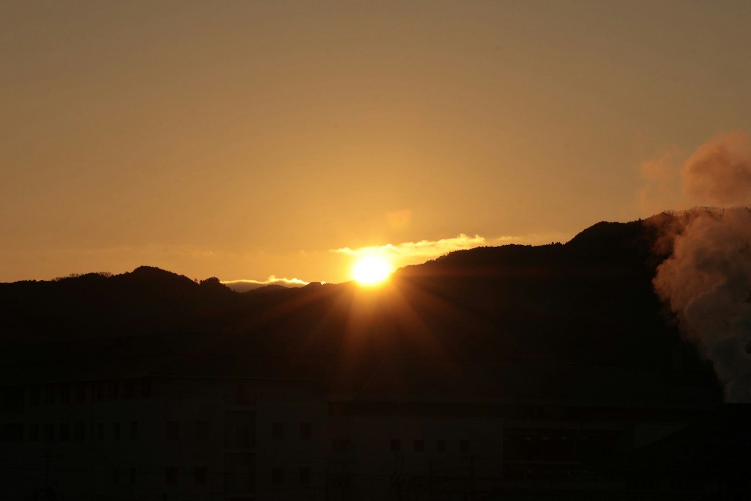 Sonnenuntergang über Bergen mit sichtbarem Rauch