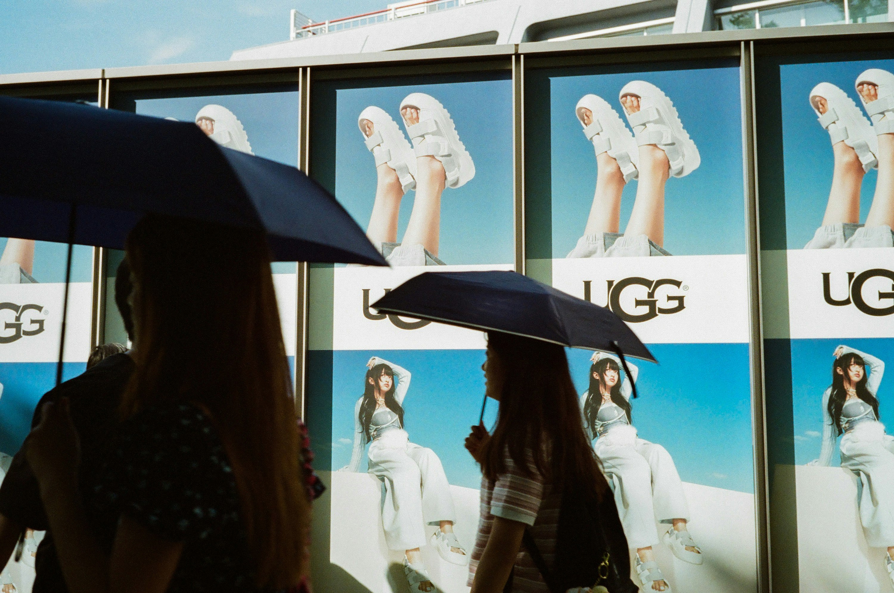 People with umbrellas in front of outdoor display panels