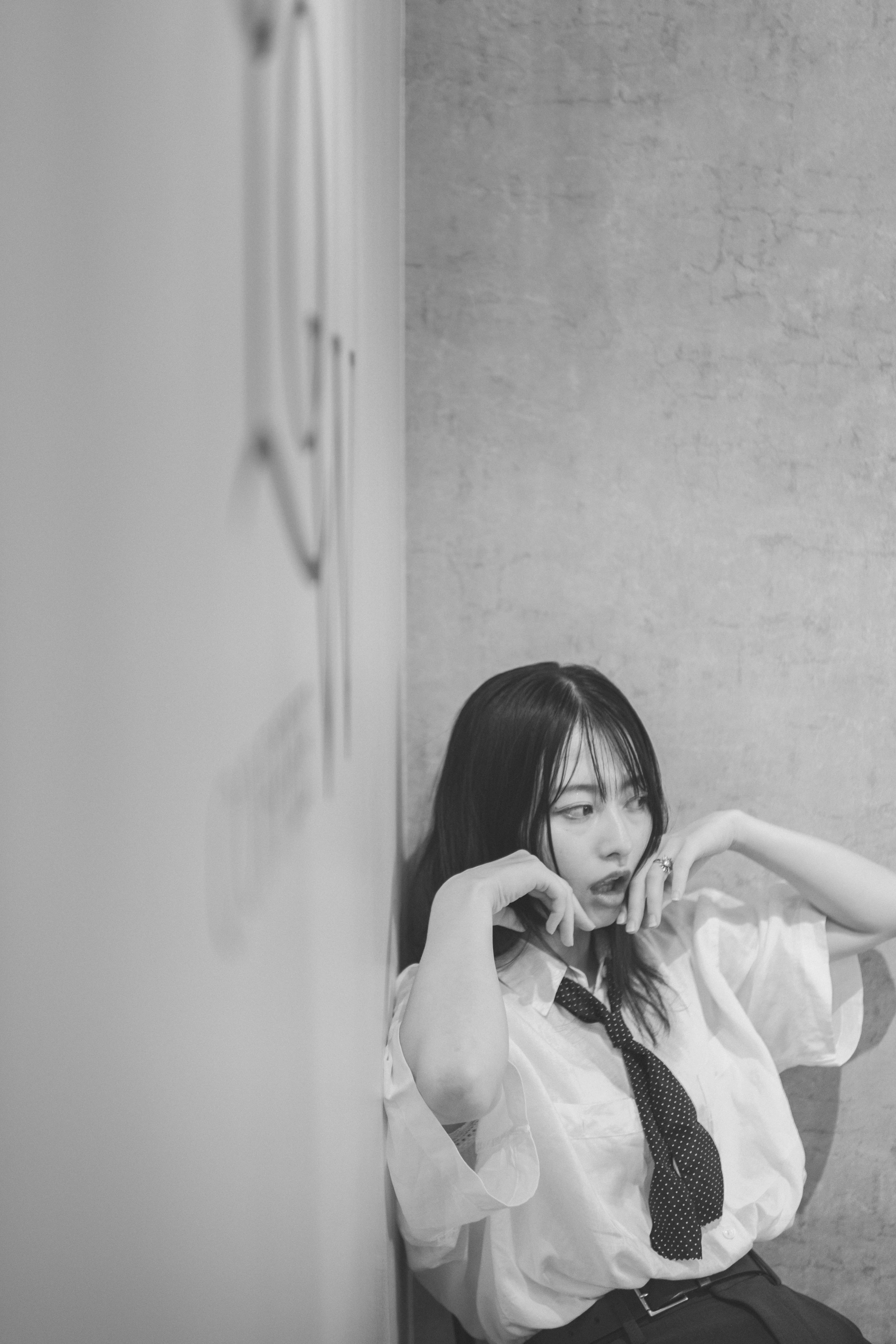 woman adjusting her tie in front of a concrete wall