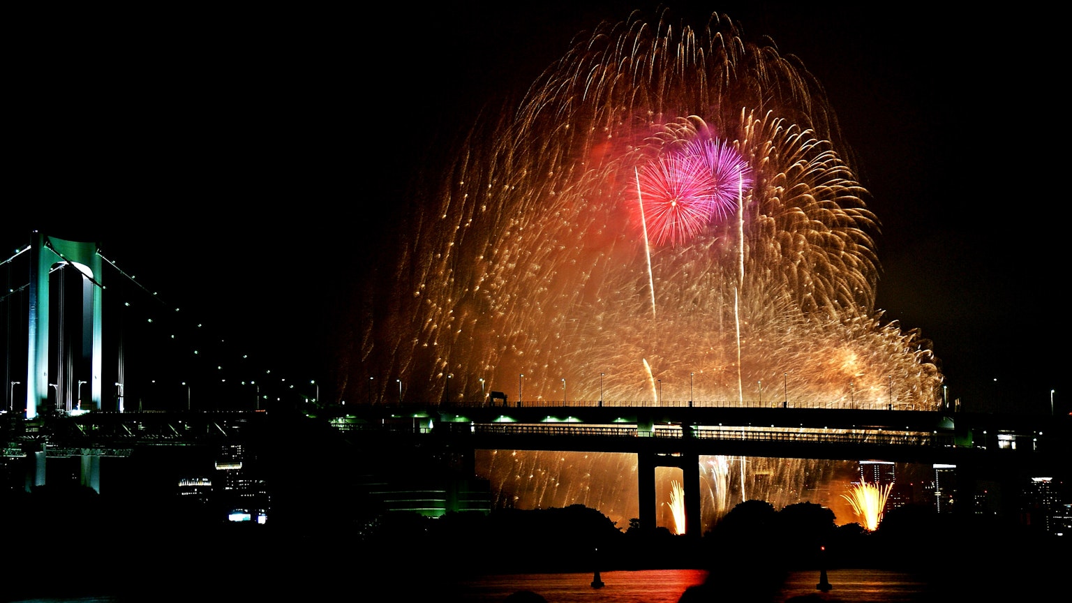Vue magnifique de feux d'artifice dans le ciel nocturne avec le pont Rainbow en premier plan