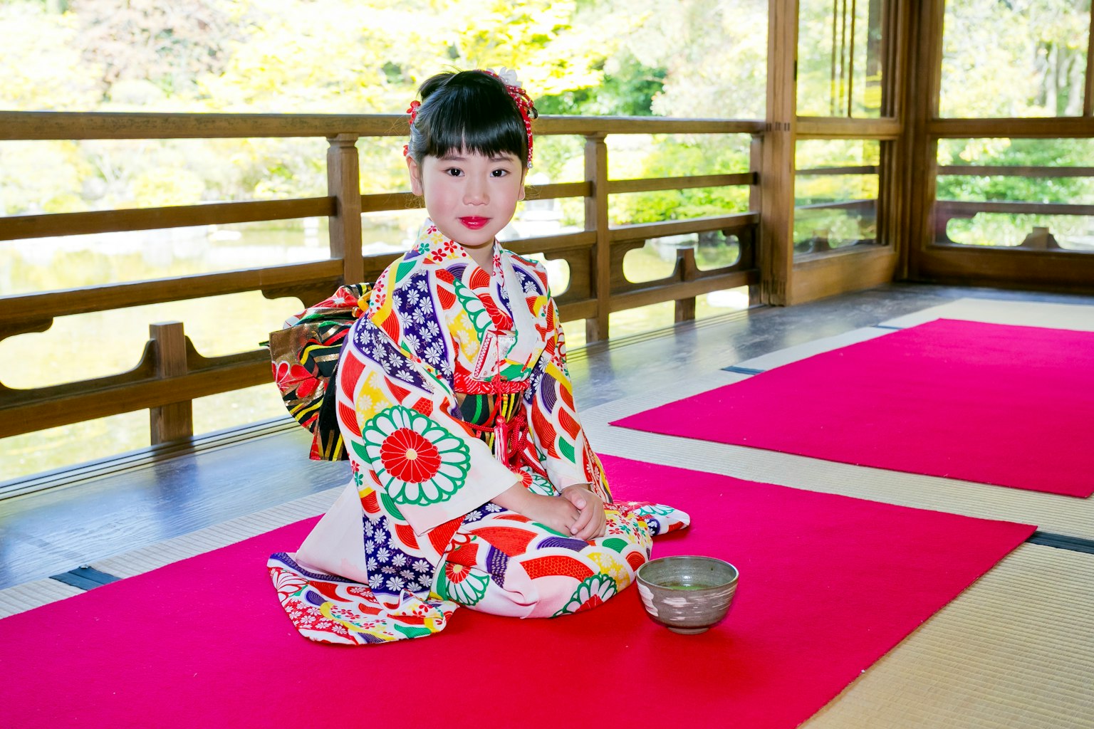 Ein Mädchen in einem bunten Kimono sitzt in einem traditionellen japanischen Raum