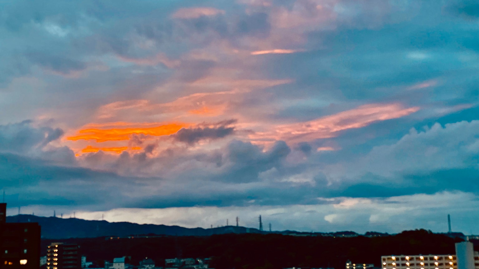 Cityscape with colorful sunset clouds and mountains in the background