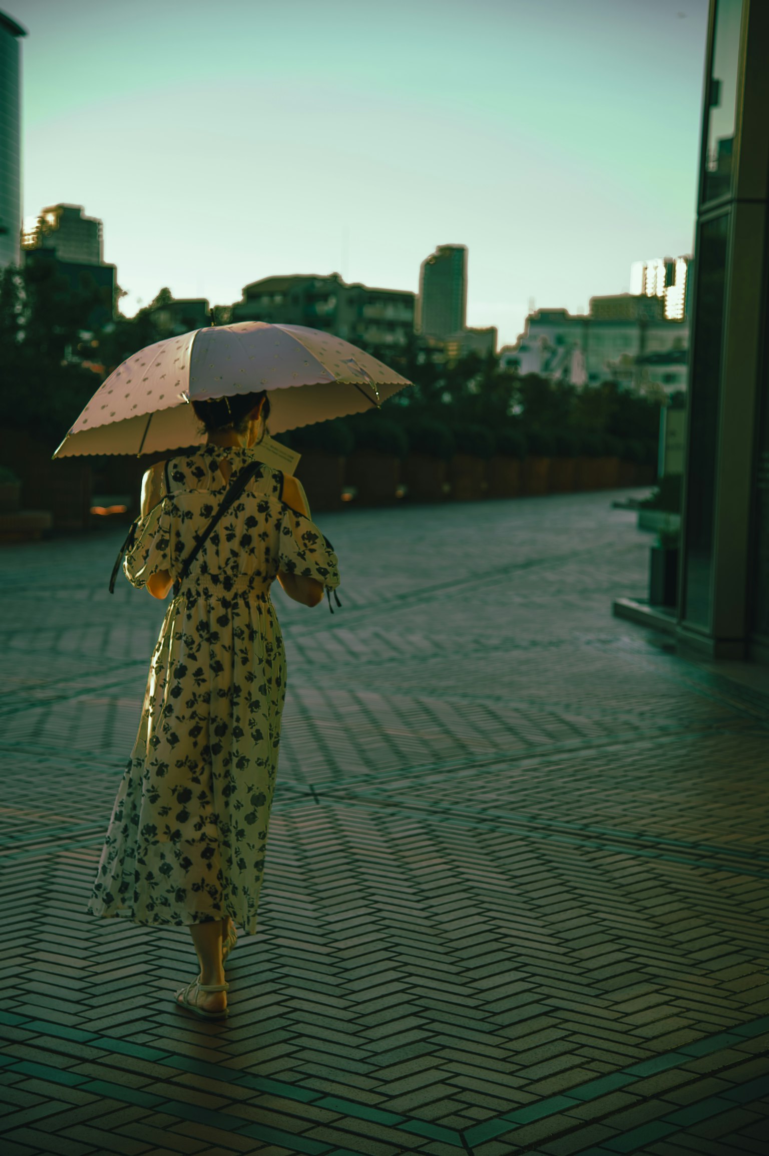 Une femme marchant avec un parapluie portant une robe jaune dans un cadre urbain