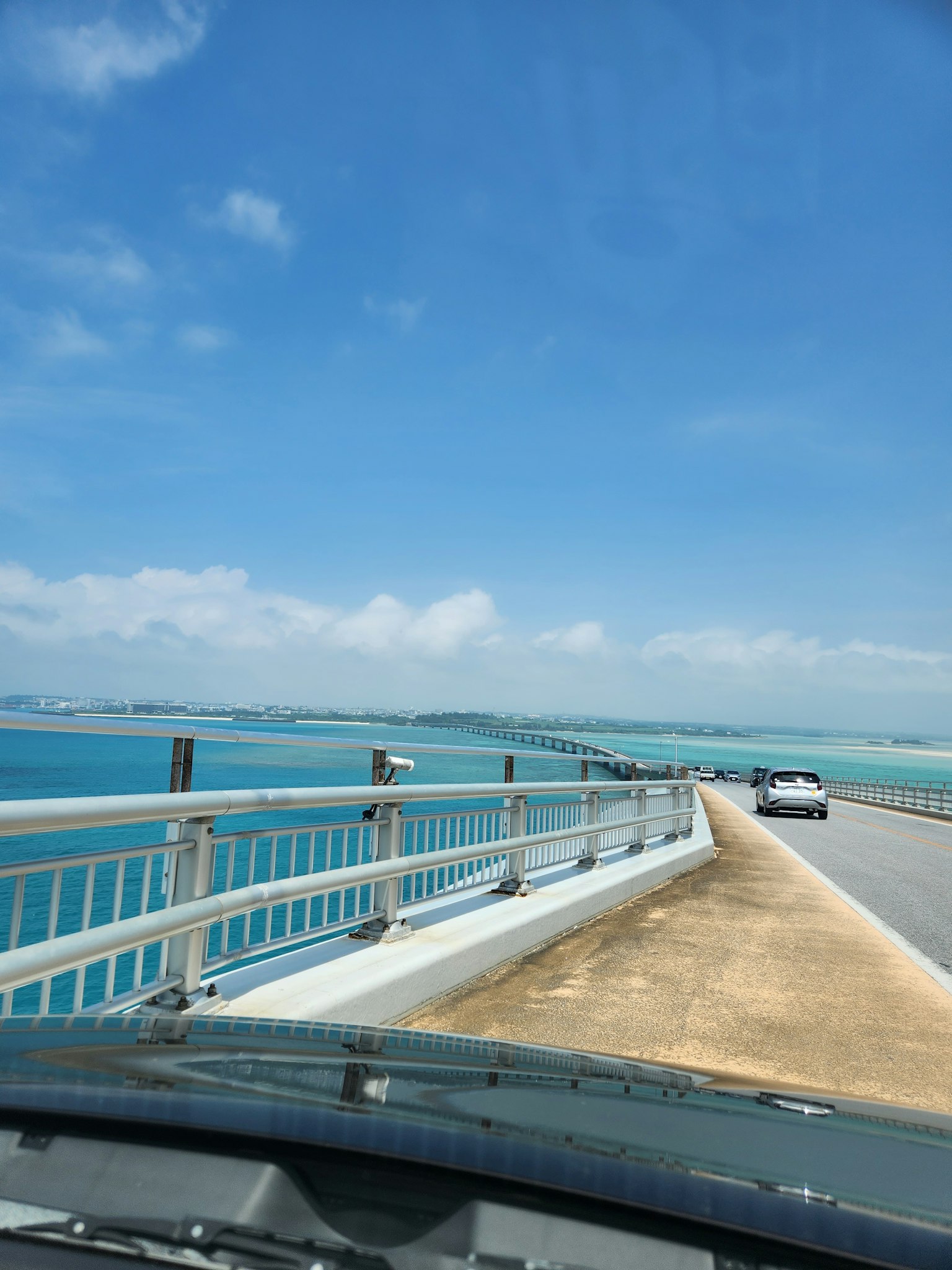 Escena de conducción en un puente con vista al mar y cielo azules