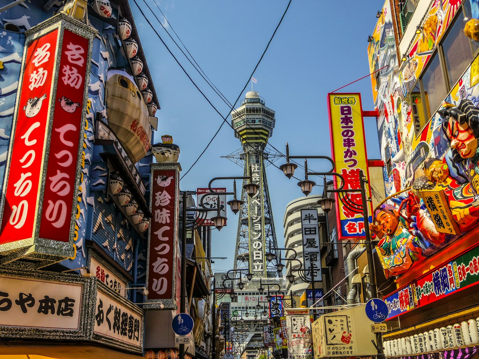 Vista della torre Tsutenkaku nelle vivaci strade di Shinsekai insegne luminose e pubblicità colorate