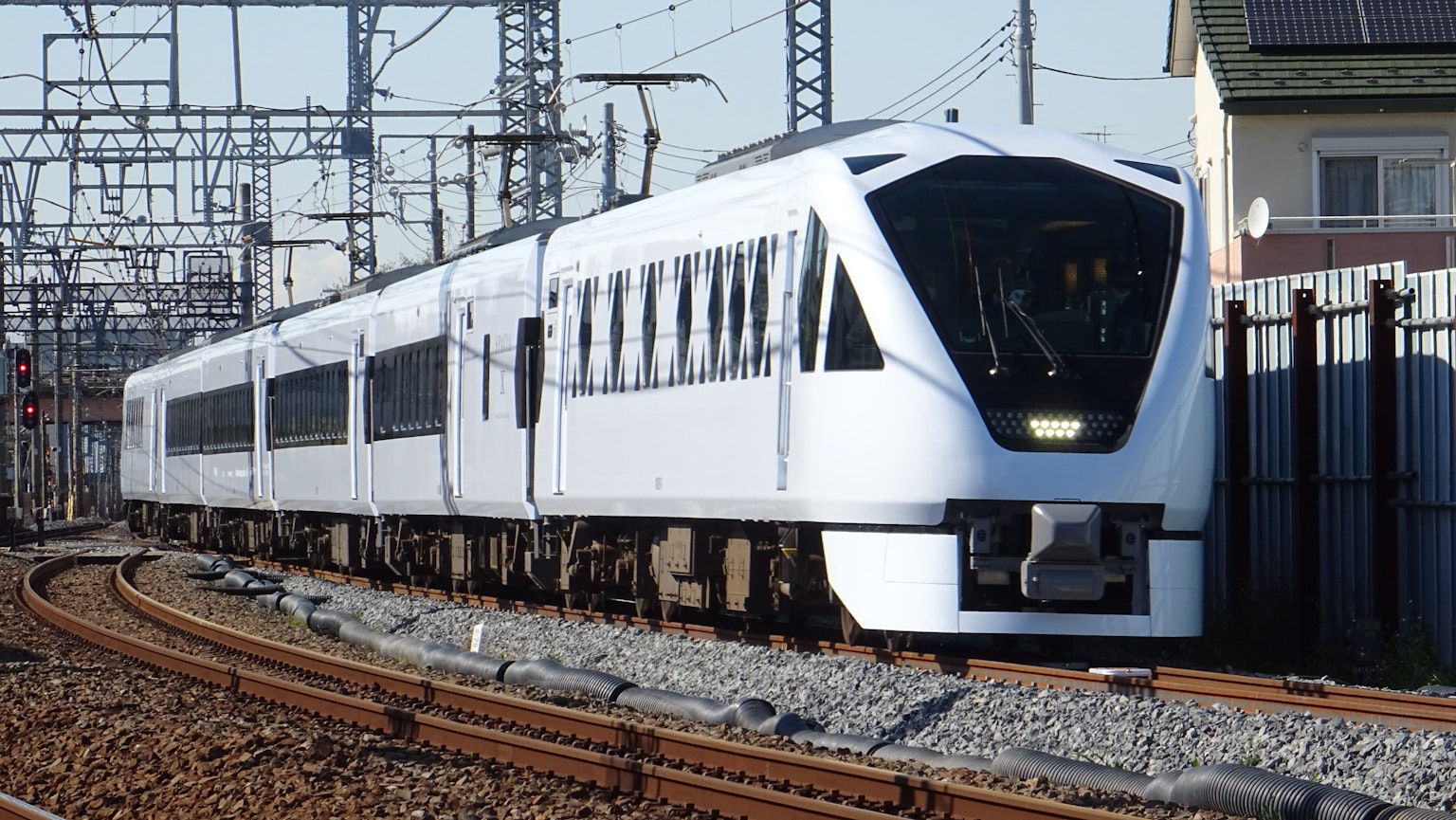 Un train blanc circulant sur des voies avec des lignes électriques en arrière-plan