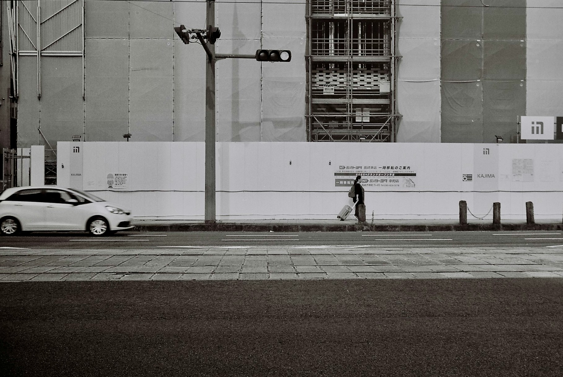 escena urbana de calle con una persona caminando junto a un muro y un coche blanco
