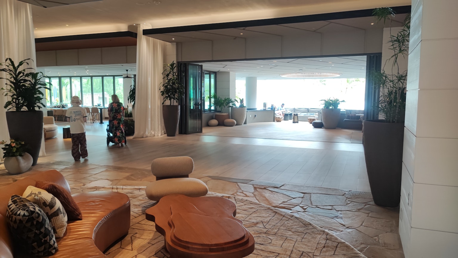 Spacious interior of a lobby featuring plants and wooden furniture bright natural light streaming in